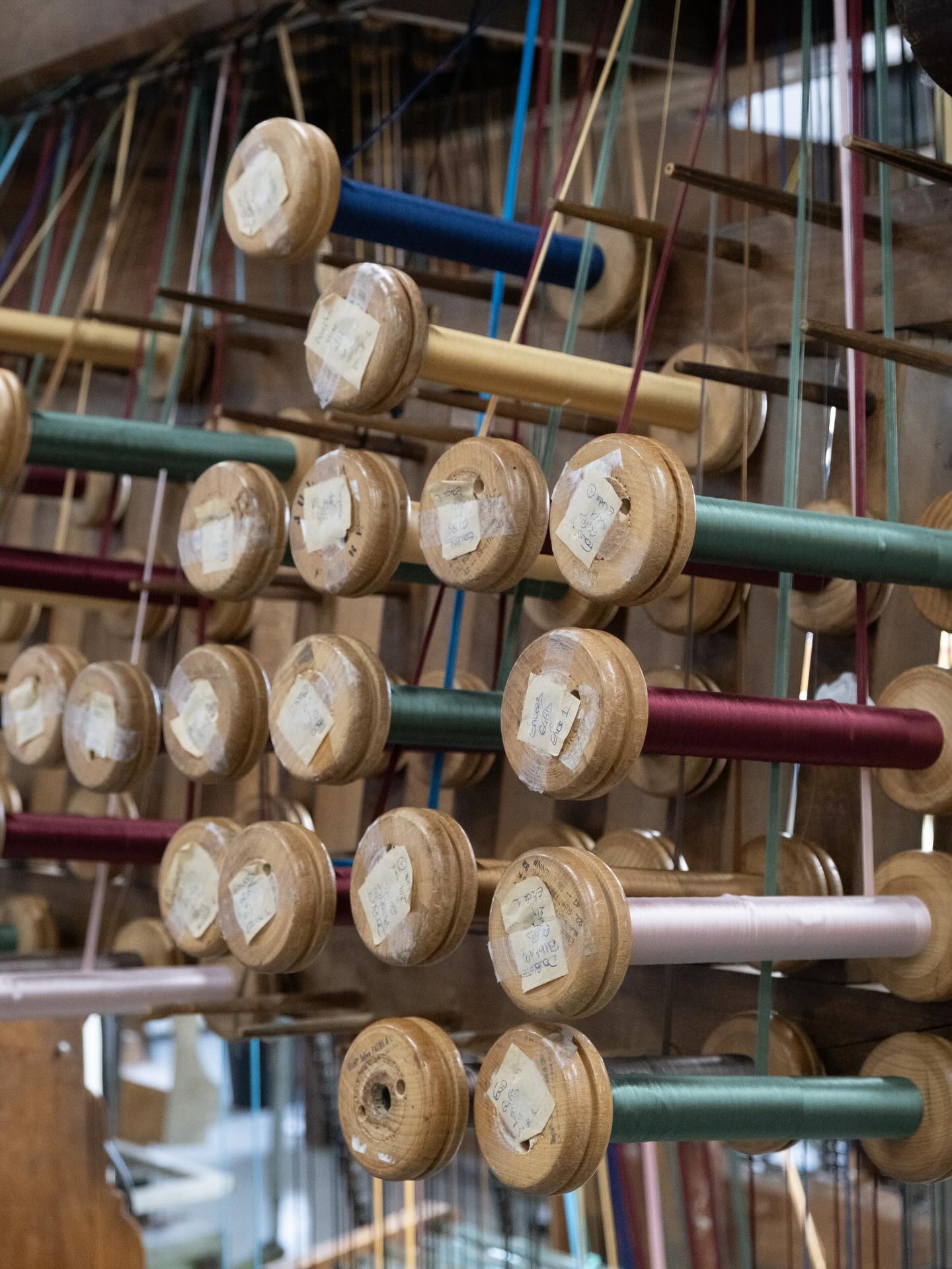 Fils de chaîne colorés passant sur des guides en verre de métier à tisser