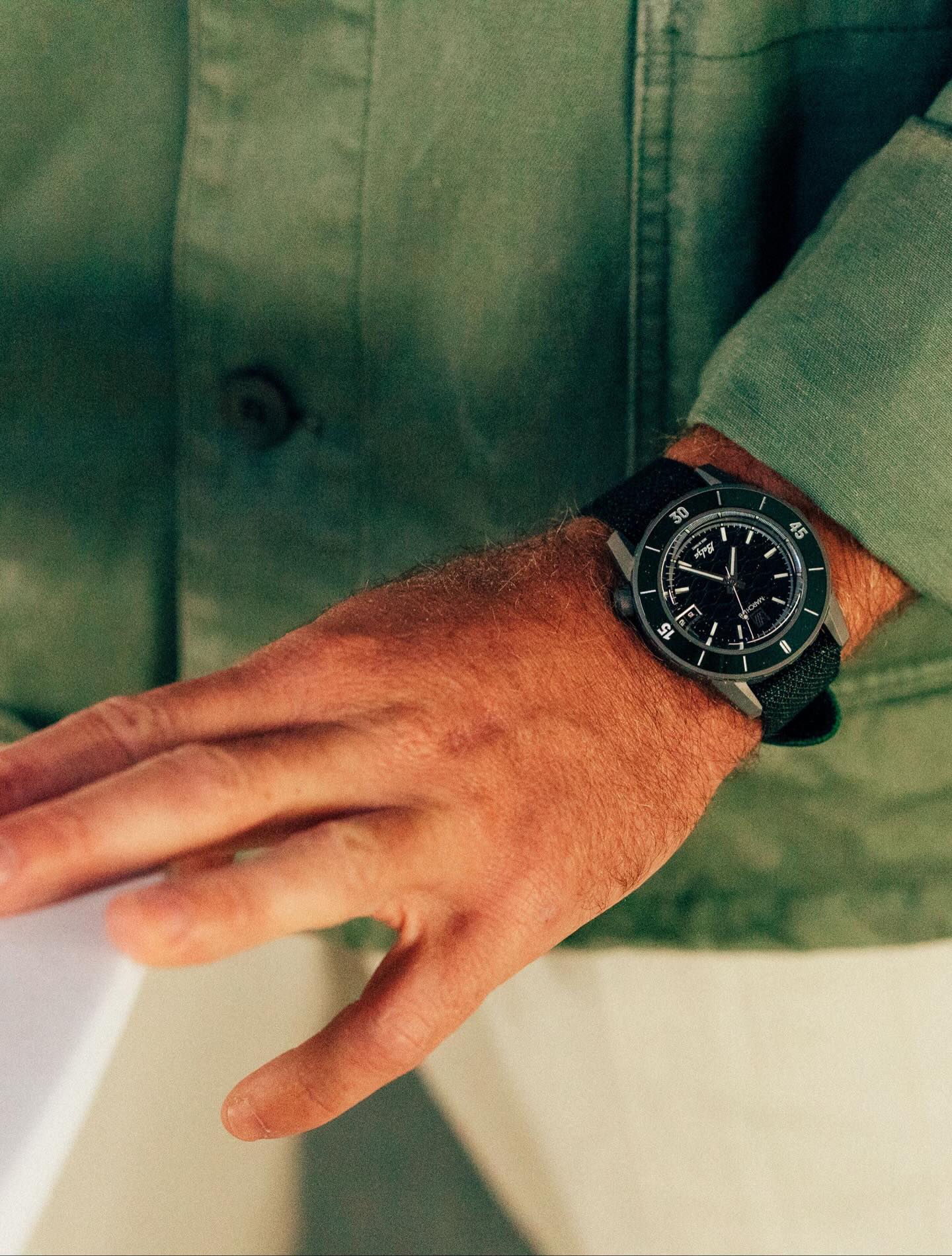 Montre March LA.B Belza portée au poignet avec une veste verte assortie