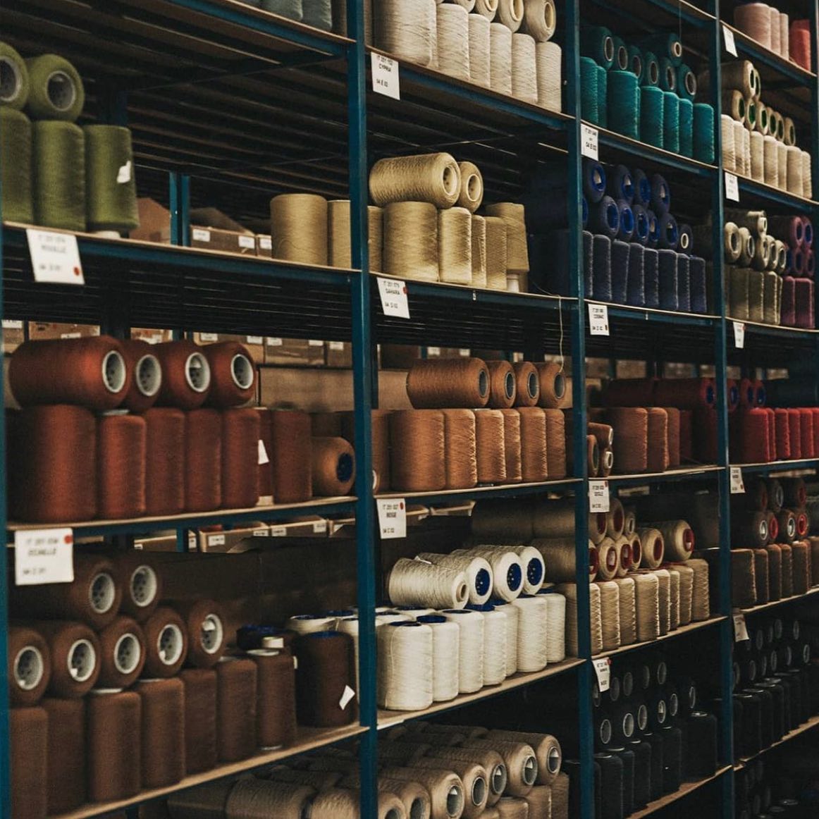 Grand stock de cônes de fils colorés rangés sur des étagères industrielles